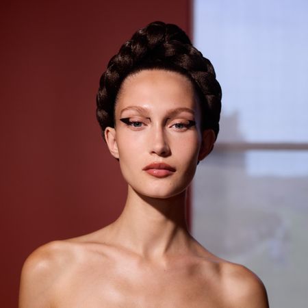 woman with an intricate braided updo, pink lipstick, and cat eye makeup