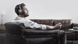 Man wearing Beyerdynamic headphones, sitting in a chair with his eyes closed