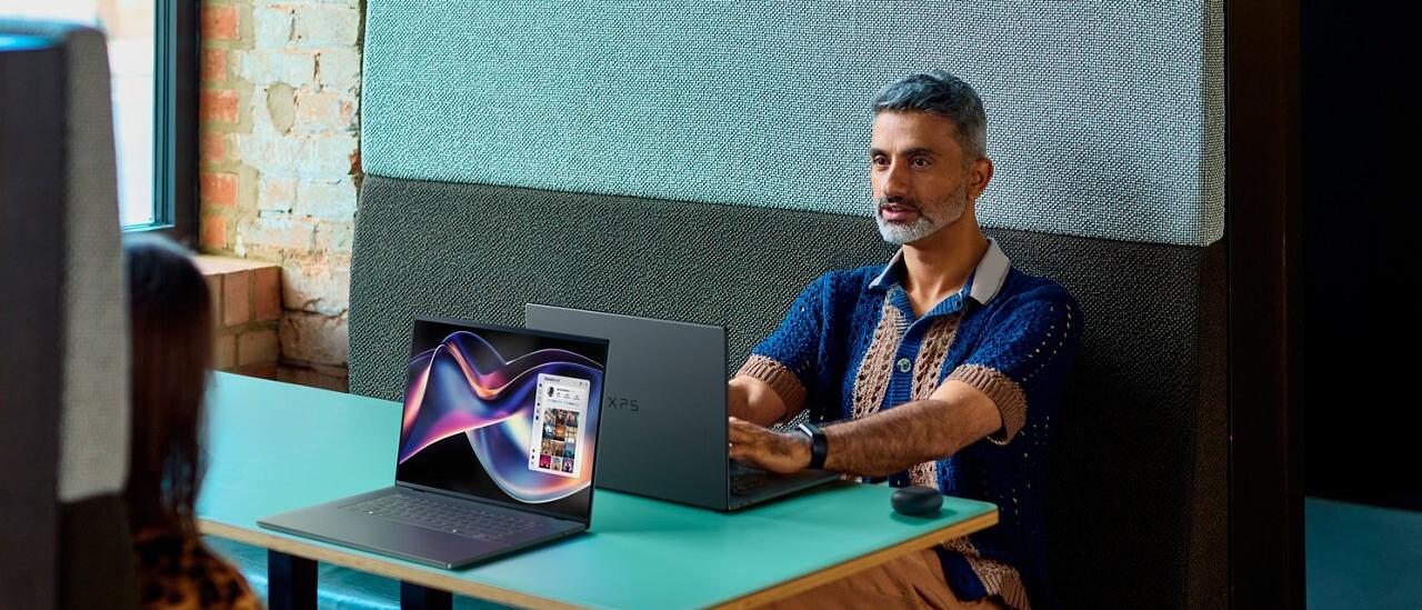 People sitting in booth with Dell XPS laptops on table