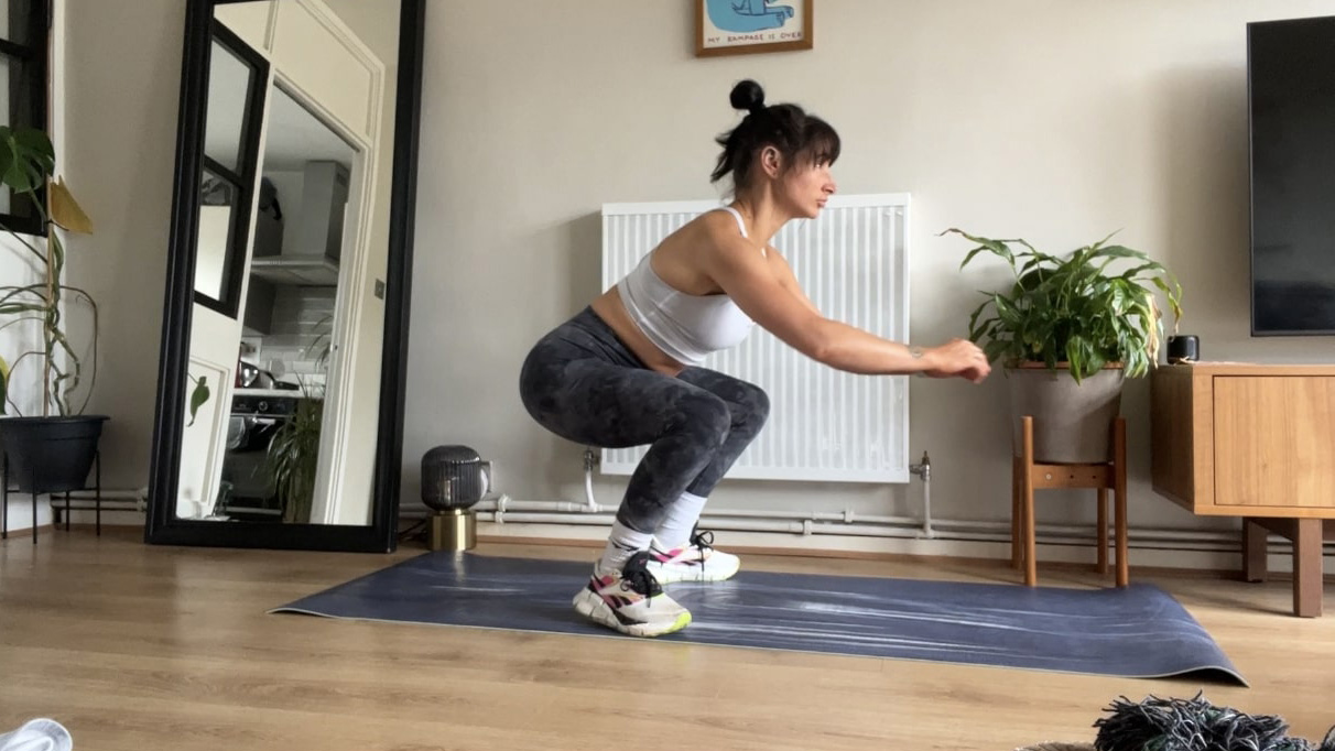 Writer Sam performing bodyweight squat at home on yoga mat