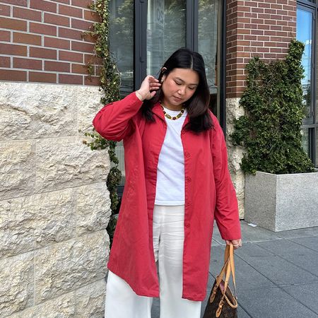 Marina wears whit linen pants, white t-shirt, and red shirt dress. Marina is also wearing a beaded necklace. 