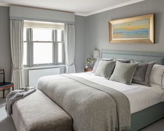 Grey bedroom with a well-styled bed and ottoman showing luxury bedroom ideas.
