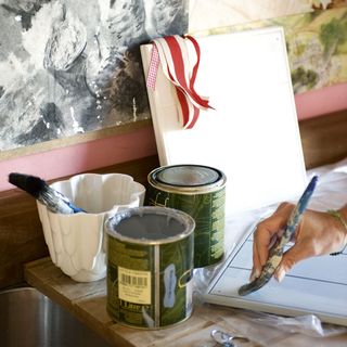 painting canvas with paint tin and brush