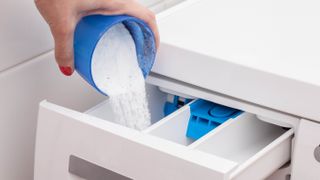 Powder laundry detergent being added to a washing machine's detergent drawer