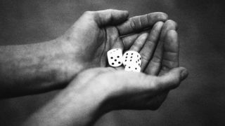 A black and white photo of hands holding a pair of dice