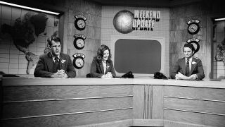 Dan Aykroyd, Jane Curtain and Bill Murray sitting at the Weekend Update desk in suits back in 1979.