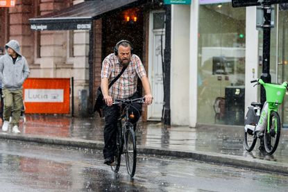  A man cycles through the rain in the UK