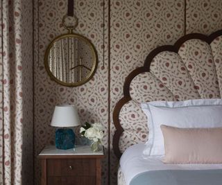 A bedroom with walls and head baord designed with the same white and red-spotted fabric