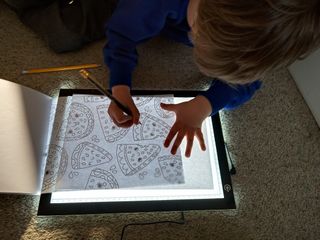 A child using the LitEnergy A4 Tracing Light Box on a floor