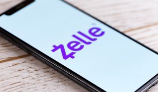 The Zelle logo in purple against a white background displayed on a smartphone screen.