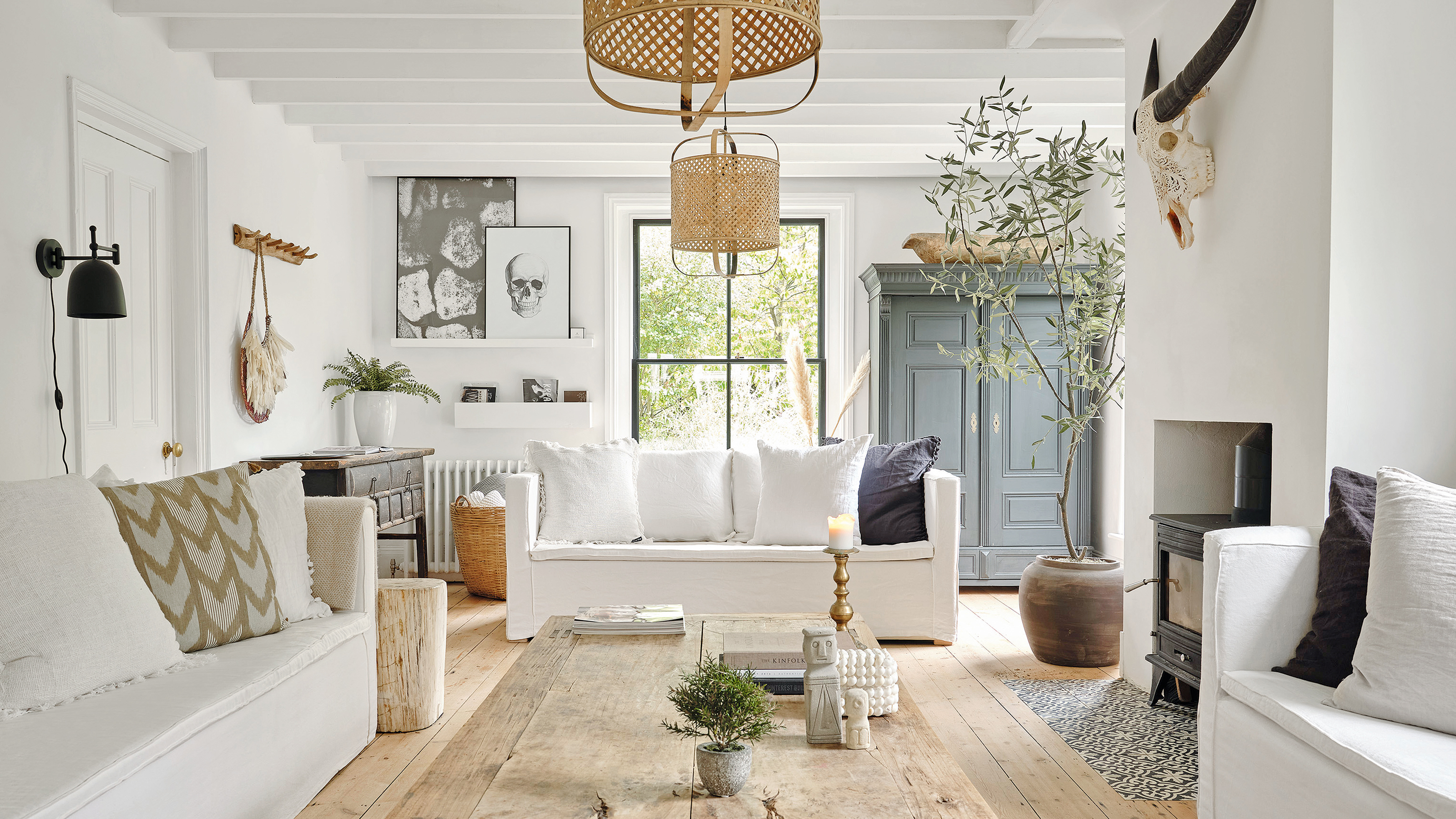 a white living room with three white sofas facing inwards, wooden flooring and a wooden dining table