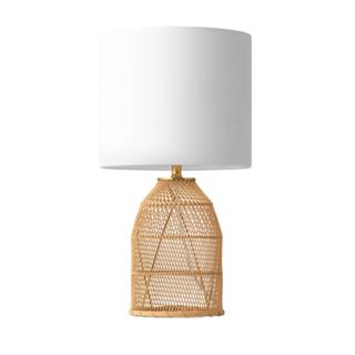 A wicker based lamp with a white lampshade