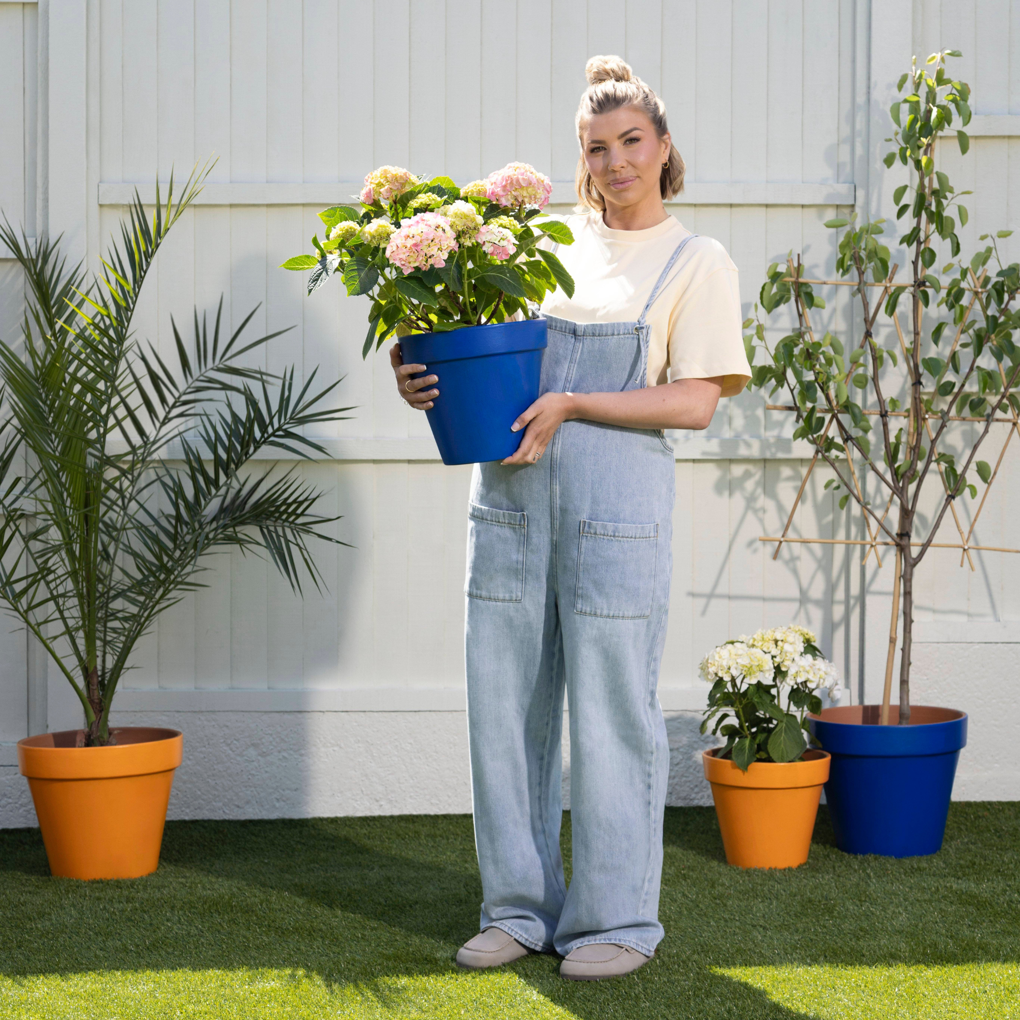 Olivia Bowen holding a blue plant pot with hydrangeas.