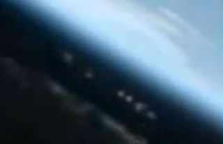 Is this an elongated UFO and accompanying fleet hovering above Earth, or a reflection?