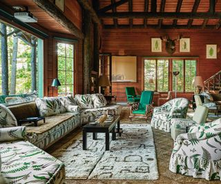 large living area with patterned sofa and rmchairs and wood paneled ceiling and walls