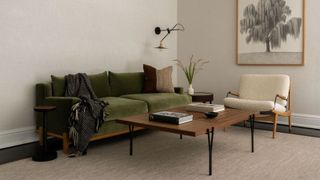 organized living room with green velvet sofa and boucle armchair