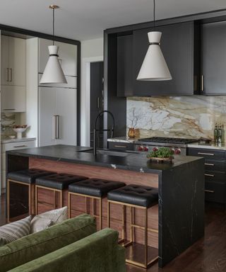 A kitchen with dark cabinetry and marble backsplash