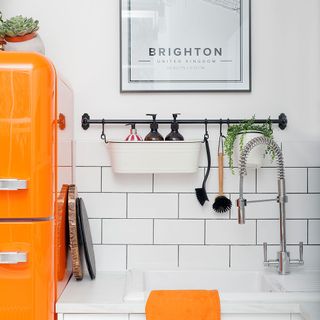 kitchen area with white wall and orange fridge and washbasin