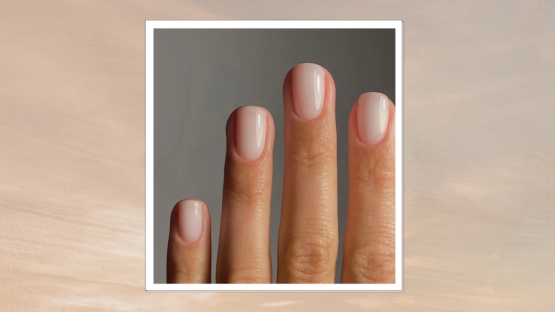 A hand is pictured with a sheer, milky white manicure but nail artist, Mateja Novakovic (@matejanova)/ in a beige to grey sunset-style template