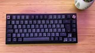 Corsair K65 Plus Wireless keyboard with no RGB on a wooden desk with a plant pot
