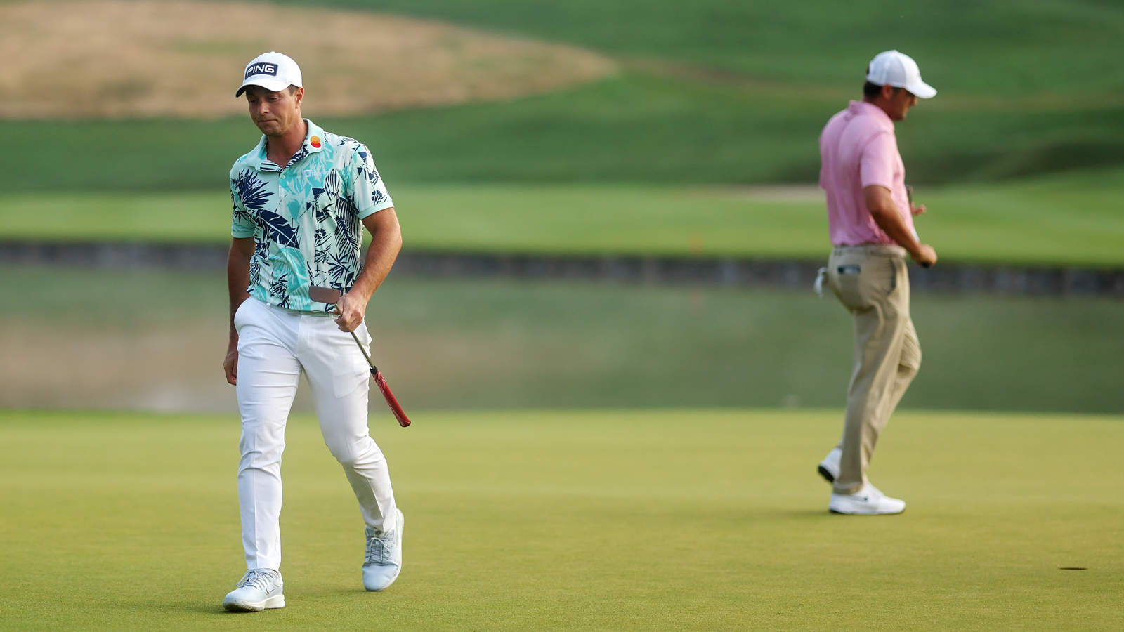 Viktor Hovland walks off the green with Scottie Scheffler behind him
