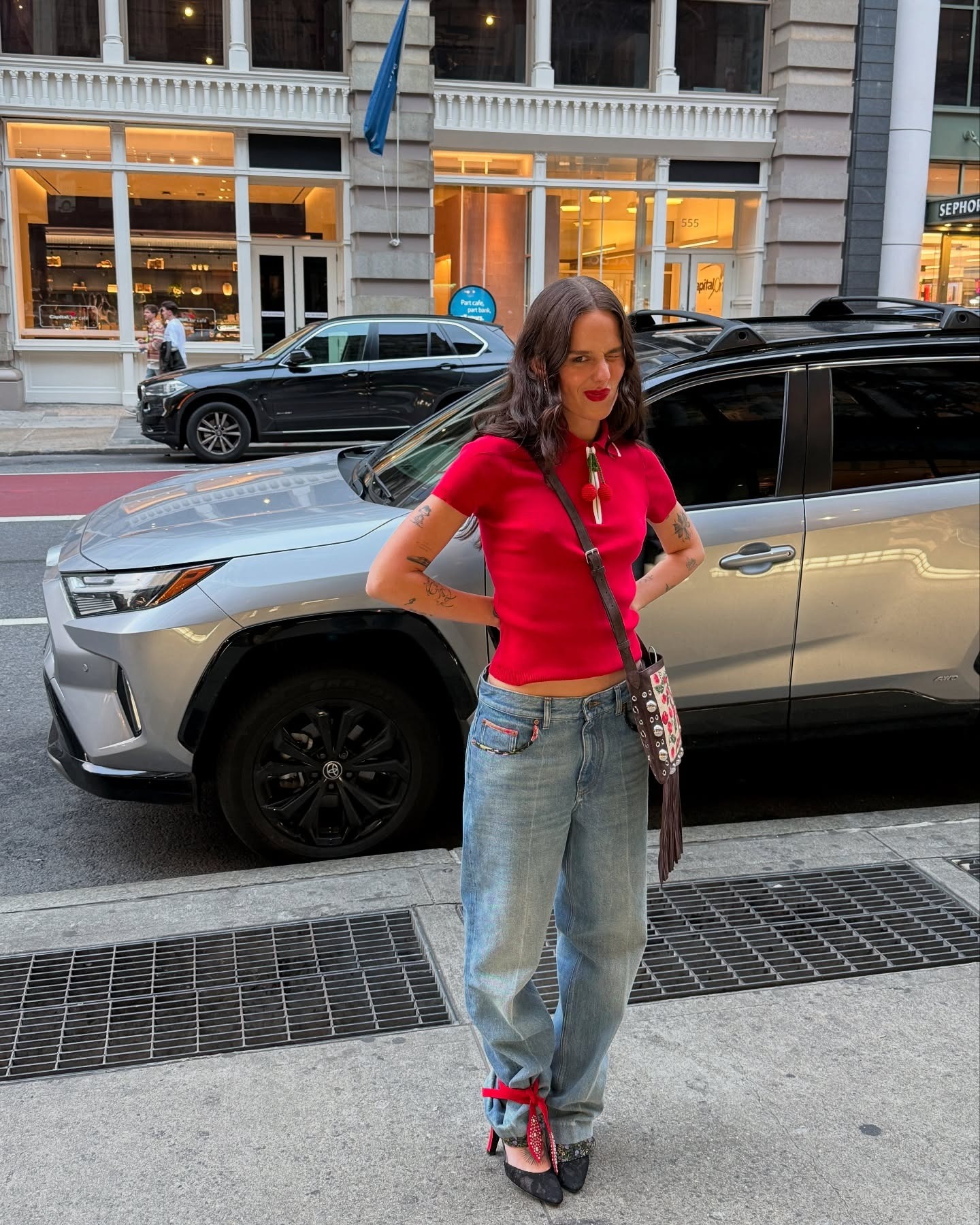A woman wearing a red polo shirt with jeans in NYC.