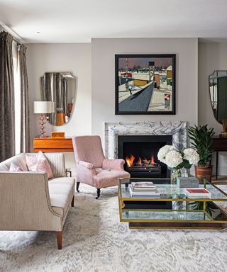 Modern living room with marble fireplace, patterned carpet, armchairs, sofa, coffee table, artwork above fireplace.