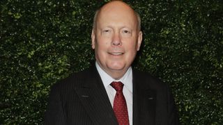 Lord Julian Fellowes in a dark suit and red tie.