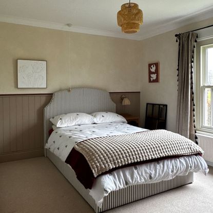 Limewashed bedroom walls with wood pannelling and stripe upholtered bed