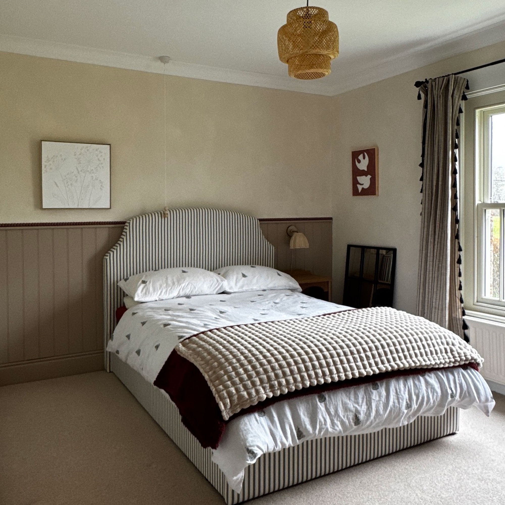 Limewashed bedroom walls with wood pannelling and stripe upholtered bed