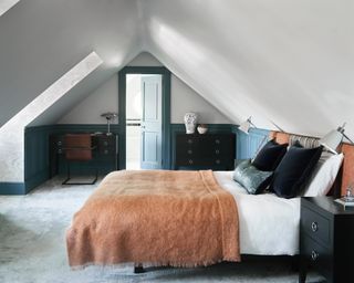 attic bedroom with dark blue paneling and clouds wallpaper inside the window reveal, and rust mohair throw