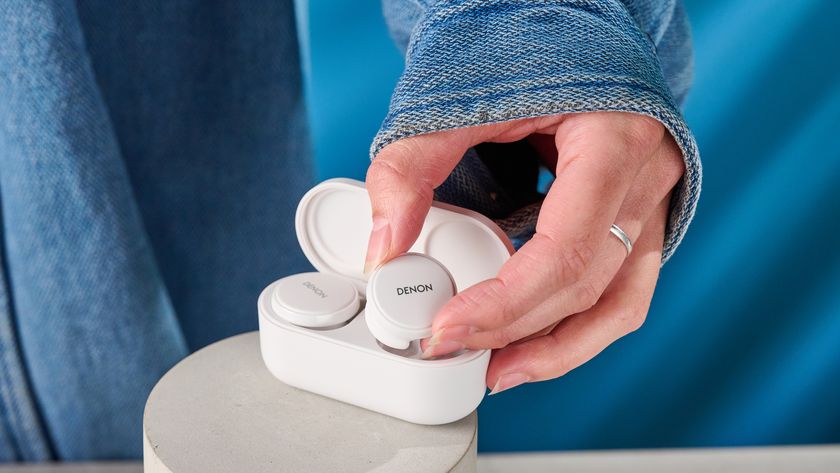 the denon perL Pro wireless earbuds in white, with circular earbud shapes, and a white charging case, photographed against a blue background
