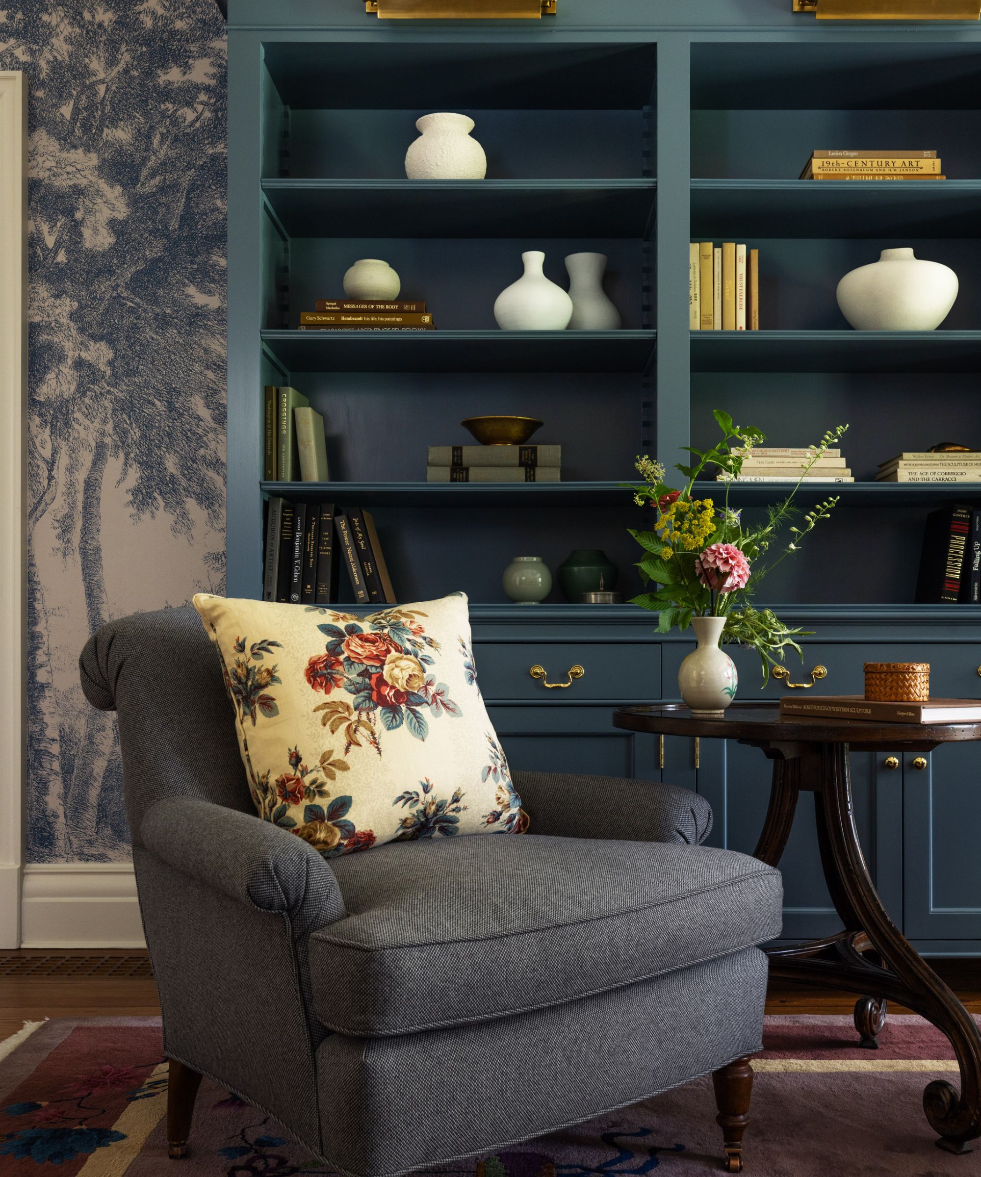 Blue living room with bookshelf, armchair and wallpaper