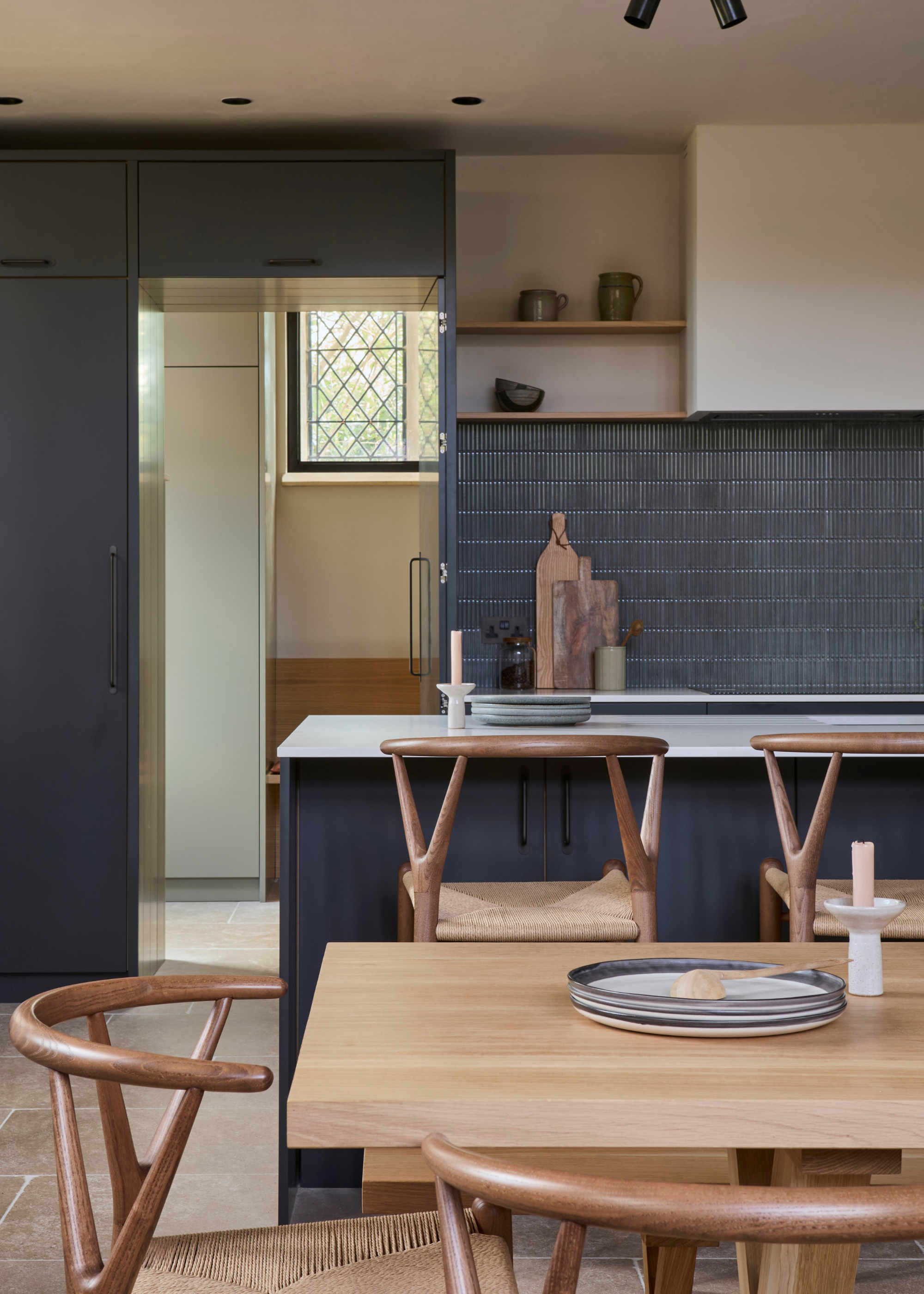a converted chapel kitchen, decorated in a shade of bluey grey with tiles and wooden rattan chairs