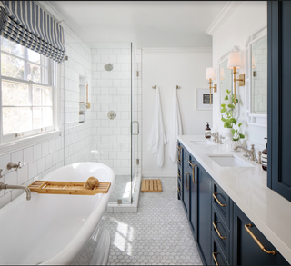 A bathroom with a roll top bath, shower enclosure and blue cabinets beneath a white vanity countertop