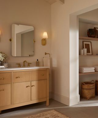 A bathroom with an open doorway, wooden vanity and rectangular mirror