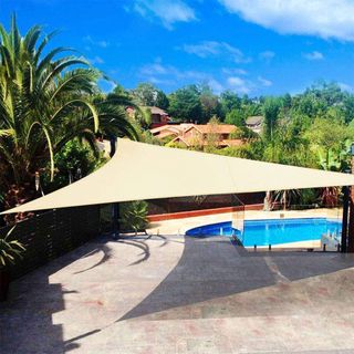 cream shade sail on a patio overlooking a pool