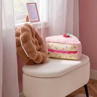 A bedroom with a boucle storage bench and a cake and a biscuit-shaped cushion on top