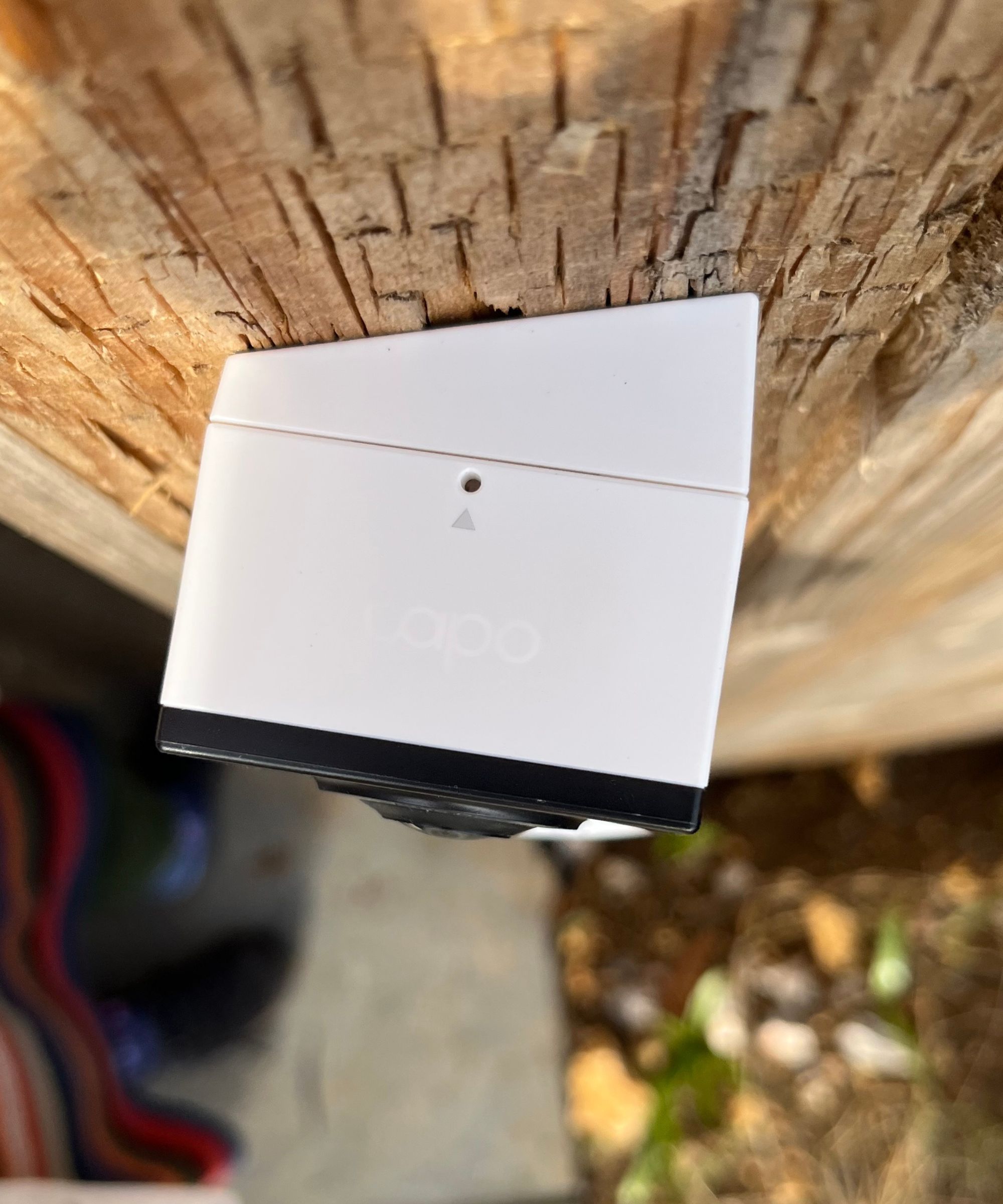 Above photograph of the Tapo D210 Video Doorbell mounted on a wedge mount, on a wooden surface.