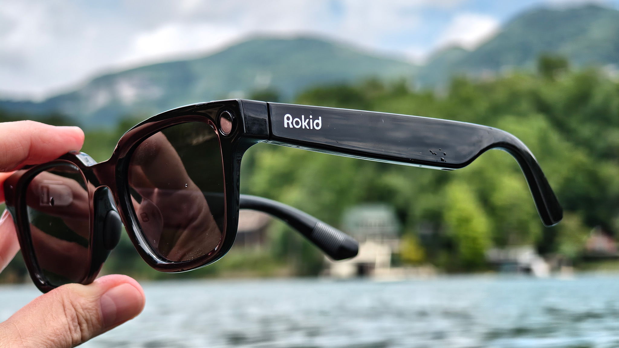 Holding a pair of Rokid AI Glasses while swimming in a lake