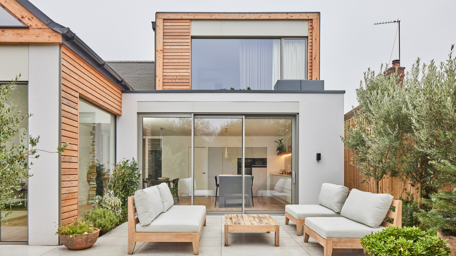 modern rendered house with loft conversion featuring timber clad front and large windows