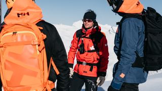Skiers chat with ski patrol wearing Helly Hansen ULLR RS30 backpack