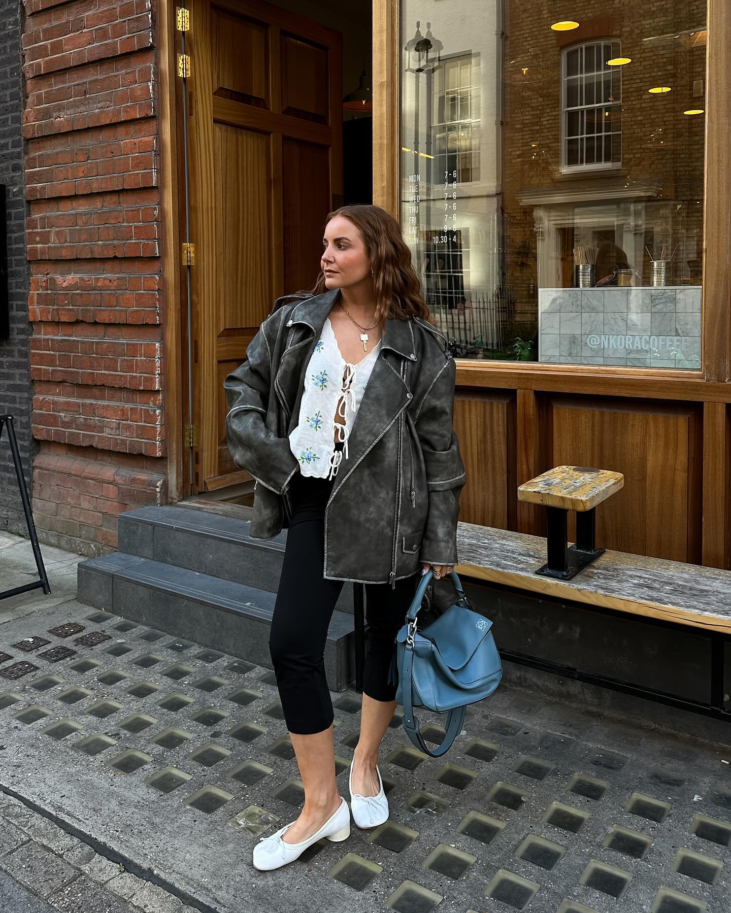 An image of @rebeccaferrazwyatt wearing an Aquamarine Loewe Puzzle bag with a black leather jacket, capri pants and ballet pumps while in London.