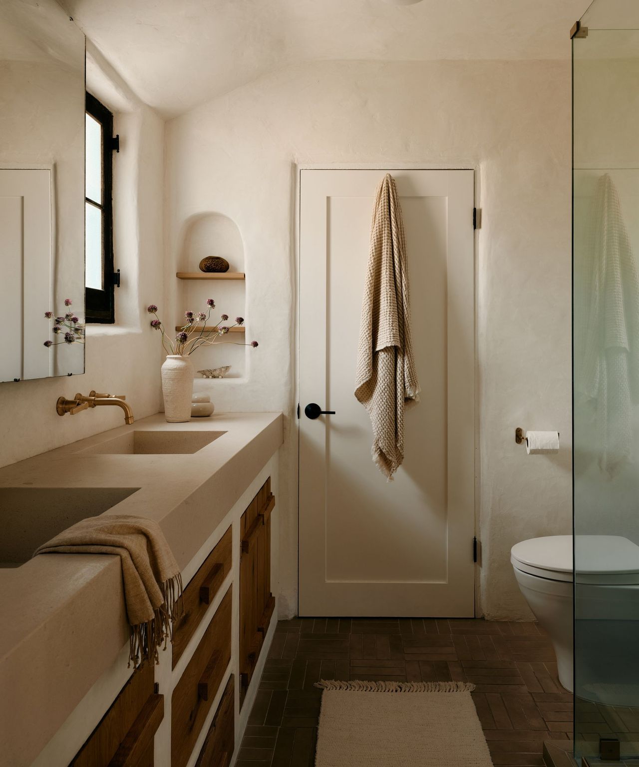 A modern organic bathroom in an Adobe home with plastered walls and a plaster and reclaimed wood vanity