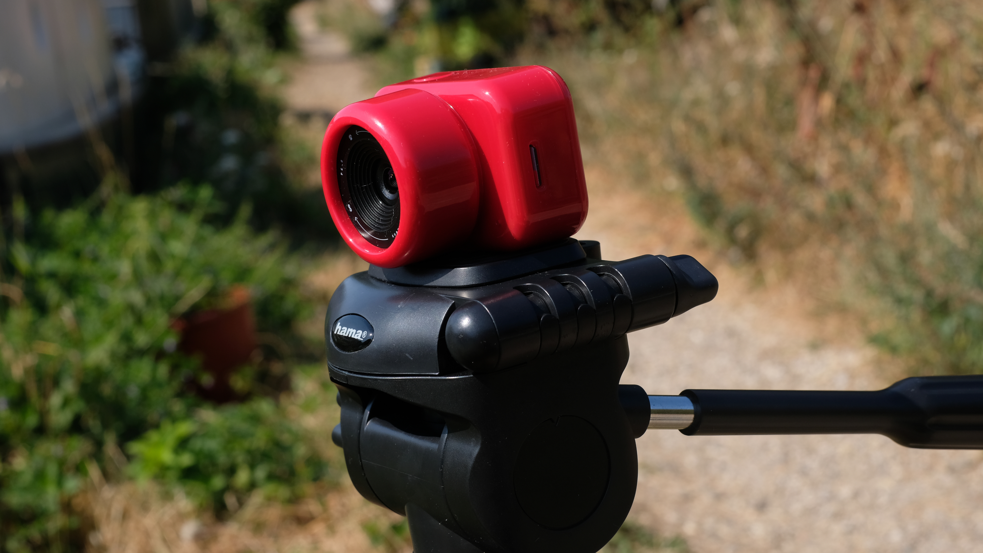 Photograph of the ATLi Eon time-lapse camera in red mounted on a tripod
