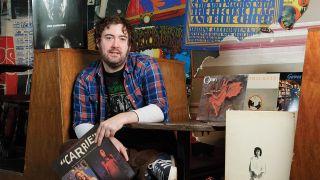 a portrait of Nick Helm with his records