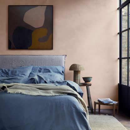 A bedroom with a blue bed and pink walls