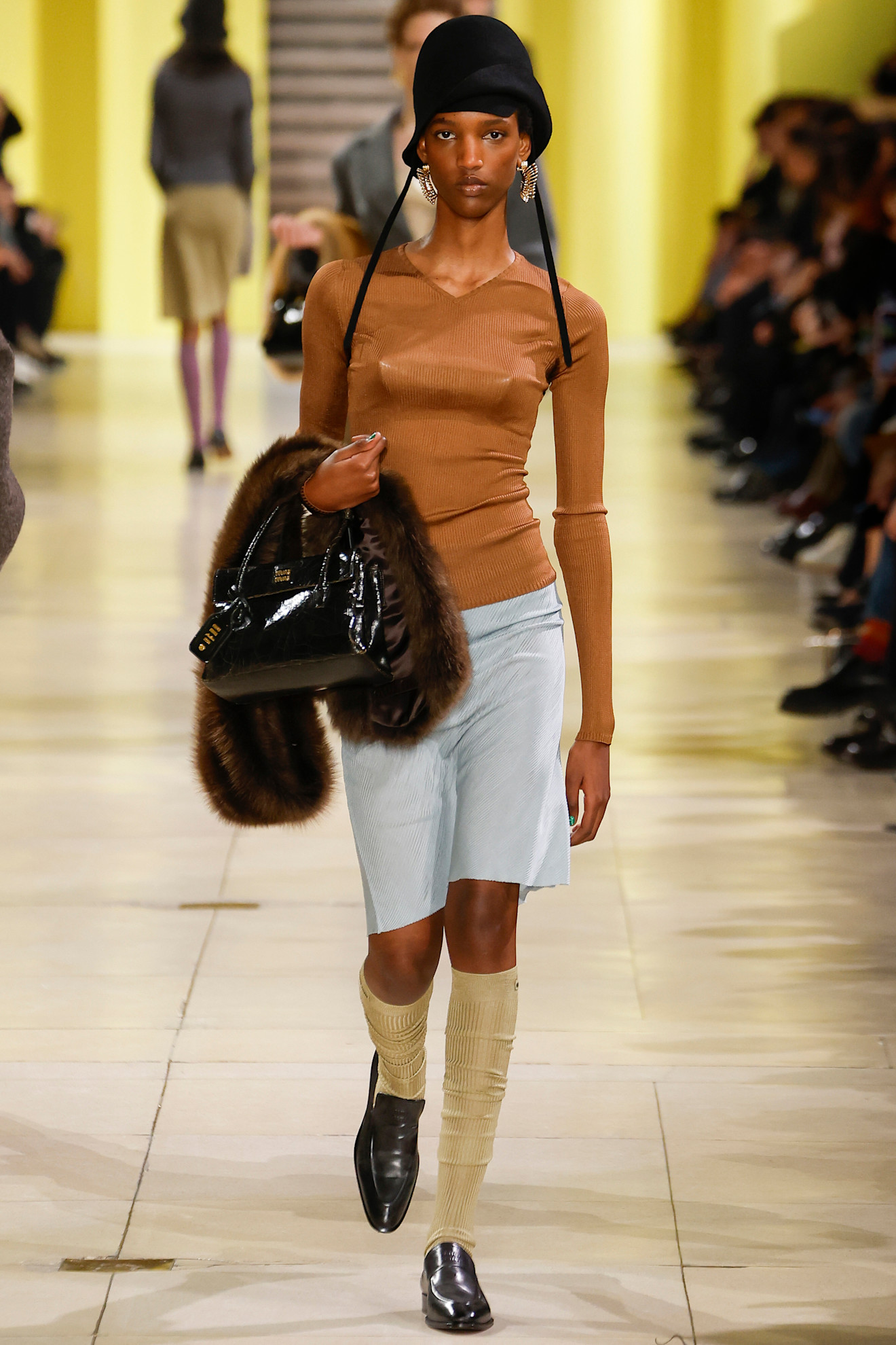 A Miu Miu model carries a fur shawl at the F/W 25 show.