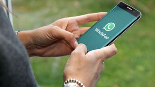 una persona sosteniendo un teléfono con el logotipo de WhatsApp