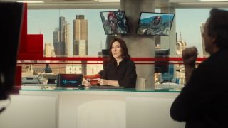 Sarah Solemani sits at the news desk during a live program in Bridget Jones's Baby.